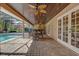 Covered outdoor living space featuring brick pavers, ceiling fans, and an outdoor kitchen overlooking the screened-in pool at 8620 Willow Kane Ct, Orlando, FL 32835