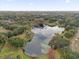 Overhead image of a neighborhood pond surrounded by trees and green landscape, under a bright skyline at 8620 Willow Kane Ct, Orlando, FL 32835