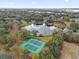 An aerial view of neighborhood tennis courts near a pond with cloud reflections, surrounded by green landscape at 8620 Willow Kane Ct, Orlando, FL 32835