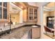 Chic bar area with granite countertops, wooden cabinets, glass shelving, and a wine cooler at 103 Arrowhead Ct, Winter Springs, FL 32708