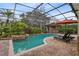 Backyard pool featuring brick pavers, lush landscaping, rock waterfall, and screened-in enclosure at 103 Arrowhead Ct, Winter Springs, FL 32708