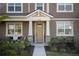 Front entrance of townhome, featuring a beige door and stone pillars at 11574 Buoy Point Pl, Orlando, FL 32832