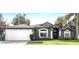 Gray house with white garage door, landscaping, and columns at 1210 Kenway Ave, Deltona, FL 32738