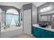 Bathroom with teal vanity, soaking tub, and walk-in shower at 16143 Palmetto Hill St, Clermont, FL 34714