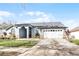 Front view of a charming one-story home with a white garage door at 16143 Palmetto Hill St, Clermont, FL 34714