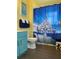 Bathroom with teal vanity, white toilet, and shower with a Disney castle shower curtain at 4560 Yellowgold E Rd # 108, Kissimmee, FL 34746