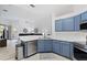 Open kitchen with island, stainless steel appliances, and blue cabinets at 627 Copeland Dr, Haines City, FL 33844