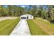 Aerial view of a home featuring a paved driveway, lush lawn, and beautiful surrounding trees at 9095 Sw 125Th Ter, Dunnellon, FL 34432