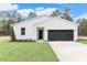 White farmhouse-style home with black garage door and landscaped lawn at 9095 Sw 125Th Ter, Dunnellon, FL 34432