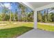 Covered patio area overlooking a spacious lawn and a lush green wooded area at 9095 Sw 125Th Ter, Dunnellon, FL 34432
