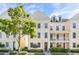 Tan three-story townhome with white columns, red door, and landscaping at 1407 Chatfield Pl, Orlando, FL 32814