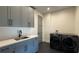 Modern laundry room features gray cabinetry, a sink with stylish faucet, and sleek, high-efficiency washer and dryer at 16902 Vinci Way, Montverde, FL 34756