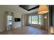 Well-lit living room with hardwood floors, large window, TV, neutral curtains, and pendant lighting at 16902 Vinci Way, Montverde, FL 34756