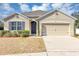 Tan house with gray roof, landscaping, and two-car garage at 2860 Ne 42Nd Rd, Ocala, FL 34470