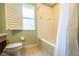 Bathroom with a white tiled tub-shower combo, window, and toilet with a wood vanity on the left at 3632 Calabria Ave, Davenport, FL 33897