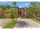 Two-story home exterior with large, mature palm trees, brick driveway, and brown facade at 3632 Calabria Ave, Davenport, FL 33897