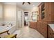 This luxurious bathroom features a soaking tub, tiled floors, custom cabinetry and a decorative chair at 661 Cricklewood Ter, Lake Mary, FL 32746