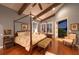 Cozy bedroom featuring a four-poster bed, beamed ceilings, hardwood floors, and tranquil exterior view at 661 Cricklewood Ter, Lake Mary, FL 32746