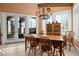 Elegant dining room with a rustic table, chandelier, and serene views through large windows and glass doors at 661 Cricklewood Ter, Lake Mary, FL 32746