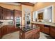 Gourmet kitchen features a central island with cooktop and dark wood cabinetry and stainless steel appliances at 661 Cricklewood Ter, Lake Mary, FL 32746