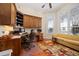 Well-lit home office featuring built-in wood cabinets, large windows, and a comfortable seating area at 661 Cricklewood Ter, Lake Mary, FL 32746