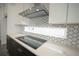 Kitchen featuring white quartz countertops, glass tile backsplash, stainless vent hood and induction cooktop at 9856 Sharpless Aly, Orlando, FL 32827