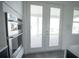 Modern kitchen featuring stainless steel appliances and sleek white cabinetry with double glass doors at 9856 Sharpless Aly, Orlando, FL 32827