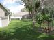 View of the backyard with mature trees and banana trees with a view of neighboring screened patios at 11618 Grand Bay Blvd, Clermont, FL 34711