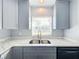 Modern kitchen featuring gray cabinets, quartz countertops, and a double stainless steel sink at 1930 Albert Lee Pkwy, Winter Park, FL 32789