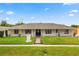 Charming single-story home featuring a well-manicured lawn, brick walkway, and classic architectural details under a bright blue sky at 3010 Bay Tree Dr, Orlando, FL 32806