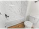 Bright bathroom featuring a tub with marble-like tile surround and wood-look flooring at 3013 Bonfire Beach Dr # 101, Kissimmee, FL 34746