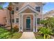 Inviting two-story home with a covered porch, a teal door and a lush, tropical landscape at 3013 Bonfire Beach Dr # 101, Kissimmee, FL 34746