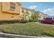 Two-story townhome with orange and yellow exterior, landscaped lawn, and parking at 346 Monroe Cir, Davenport, FL 33896