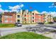 Apartment building exterior featuring brick and yellow siding, balconies, and ample parking at 5600 Devonbriar Way # 204, Orlando, FL 32822