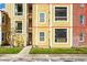 Detailed view of apartment building exterior showcasing yellow siding, balconies, and brick accents at 5600 Devonbriar Way # 204, Orlando, FL 32822
