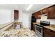 Modern kitchen with granite countertops, stainless steel appliances, and dark wood cabinets at 5600 Devonbriar Way # 204, Orlando, FL 32822