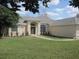 Attractive single-story home featuring a well-kept lawn, lush landscaping, and a beautiful arched entryway at 11618 Grand Bay Blvd, Clermont, FL 34711