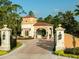 Elegant gated entrance with stone pillars, tile roof, and lush landscaping at 10601 Autumn Mist Ln # 302, Golden Oak, FL 32836