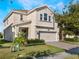 Two-story house with beige siding, three-car garage, and a landscaped lawn at 1016 Downswing Pl, Davenport, FL 33896
