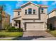 Two-story house with beige siding, three-car garage, and a landscaped lawn at 1016 Downswing Pl, Davenport, FL 33896