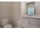 Clean powder room with white vanity, toilet, and framed mirror at 1016 Downswing Pl, Davenport, FL 33896