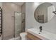 Modern bathroom with a glass-enclosed shower, round mirror, sleek sink, and contrasting black hardware for a stylish design at 10416 Pocket Ln, Orlando, FL 32836