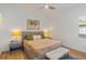 Bright bedroom with a king-size bed, hardwood floors, and a soft bench at the foot of the bed, illuminated by modern lamps at 10416 Pocket Ln, Orlando, FL 32836
