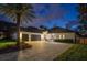 Exterior elevation of a beautiful home at dusk with a large driveway and stone accents at 10416 Pocket Ln, Orlando, FL 32836