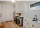 Well-equipped laundry room with modern washer and dryer, ample cabinet space, a utility sink, and hardwood floors at 10416 Pocket Ln, Orlando, FL 32836