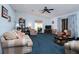 Living room with blue carpet, couches, and a ceiling fan at 1207 Palmetto Dr, Lady Lake, FL 32159