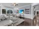 Bright living room with dark hardwood floors, large sectional sofa, floating shelves, and beach scene on the TV at 1730 Connecticut Ave, St Cloud, FL 34769