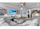 Open floor plan living room featuring a large gray sectional sofa, ceiling fan, and hardwood floors at 1730 Connecticut Ave, St Cloud, FL 34769