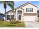 Two-story house with tan exterior, brown shutters, and a two-car garage at 290 Clydesdale Cir, Sanford, FL 32773