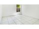 A clean, well-lit bedroom featuring white tile floors, bright white walls, and a window showing the greenery outside at 441 Tree Shore Dr, Orlando, FL 32825